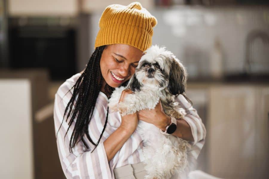 Woman hugging her Shih Tzu dog indoors, sharing a loving moment during National Pet Cancer Awareness Month with Hearts at Home Pet Sitting in Poquoson, Virginia.