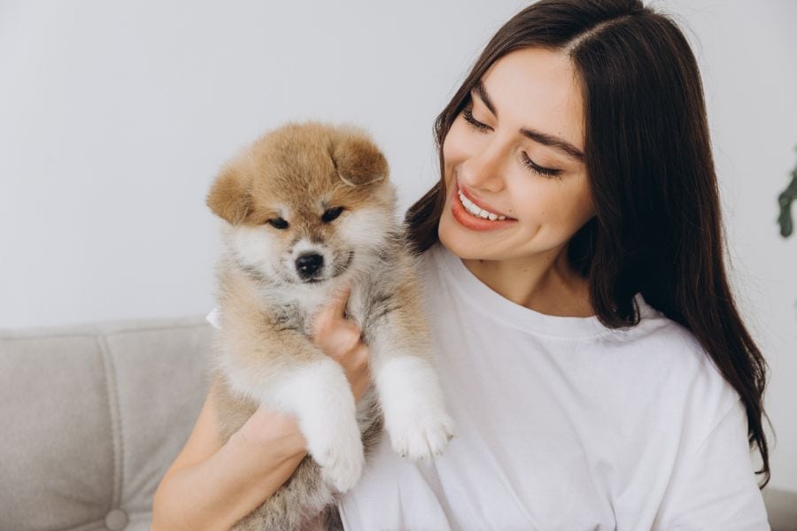 Smiling woman holding a fluffy puppy at home in Poquoson, Virginia