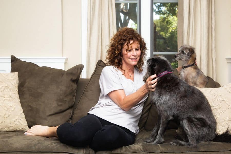 Woman sitting on a couch with two dogs during in-home pet sitting in Newport News, Virginia