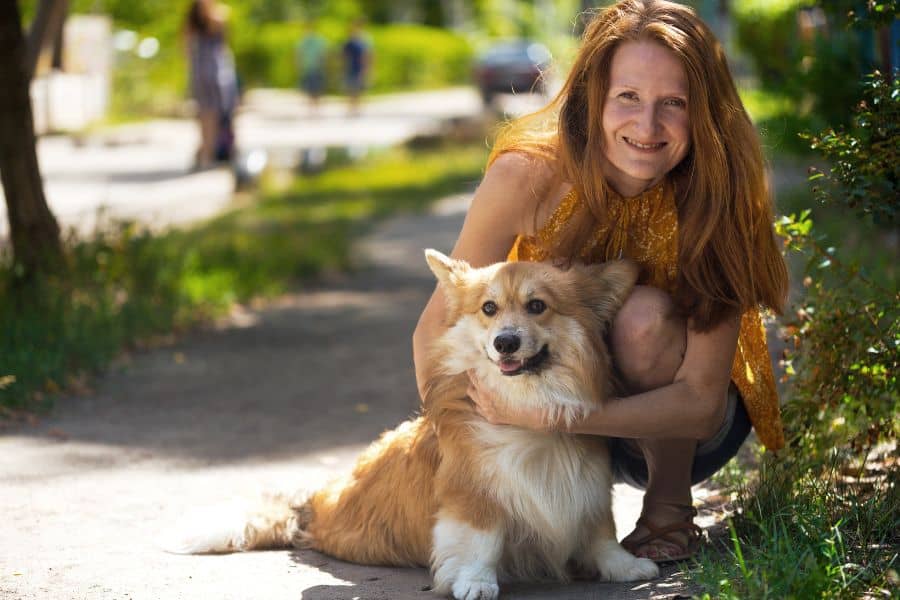 Loving pet owner with her happy border collie outdoors, showcasing reliable in-home pet sitting services.